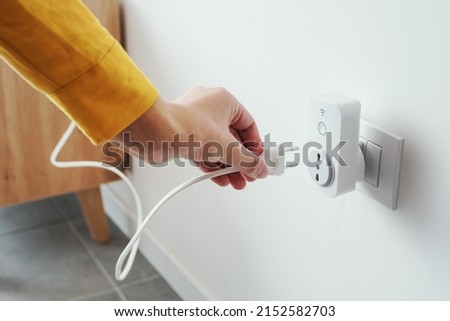 Woman plugging a device into a smart plug, virtual assistant and domotics concept Royalty-Free Stock Photo #2152582703