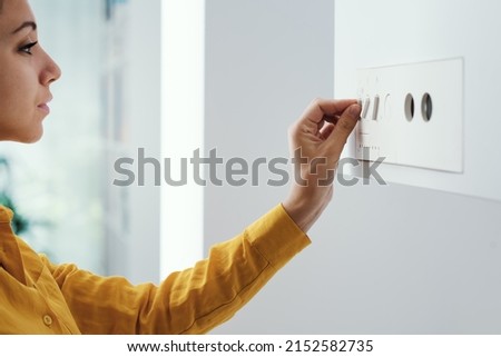 Young woman checking settings and temperature on the boiler at home Royalty-Free Stock Photo #2152582735