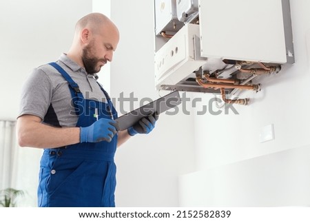 Gas engineer writing a gas safety certificate and boiler records after servicing Royalty-Free Stock Photo #2152582839