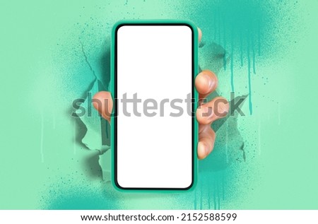 Recommending Cellular App. Male hand holding cellphone with white empty screen showing device to camera breaking through green paper sheet. Gadget display, free copy space, paint splashes and drips