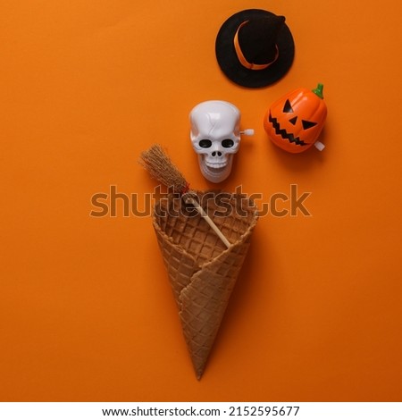 Halloween minimal layout. Waffle cone with Halloween decor on an orange background. Top view. Flat lay