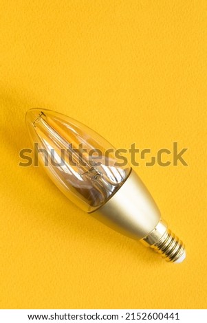 Energy saving E14 led light bulb on yellow background Royalty-Free Stock Photo #2152600441