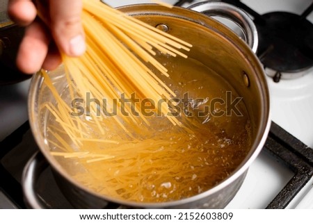 Dip spaghetti into boiling water in a saucepan. Pasta cooking. Royalty-Free Stock Photo #2152603809