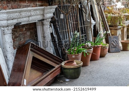 Items in an antique shop reclamation yard including wooden pediment, fire surround, planters, plaques and statues