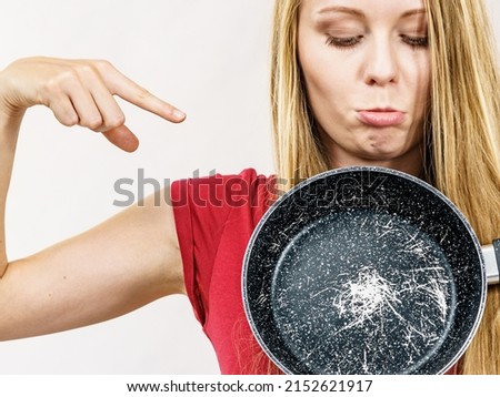 Woman holding scratched frying pan, cause of cancer. Torn coating, kitchen utensil is unusable Royalty-Free Stock Photo #2152621917