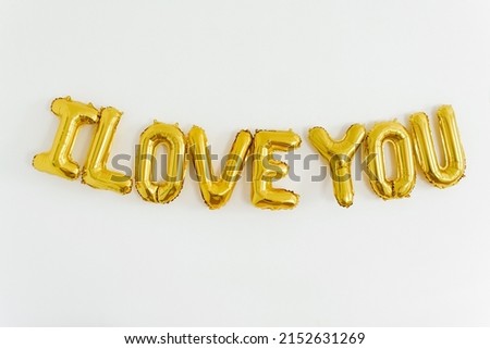 Inscription I LOVE YOU, foil inflatable gold ballon on the white background. Love, romance and Valentines day concept. Flat lay with copy space