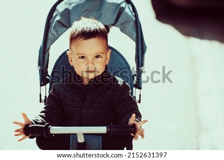 Sweet baby boy in a stroller bicycle outdoors. Little child in a pram. Infant kid in a pushchair. Spring walks with kids.