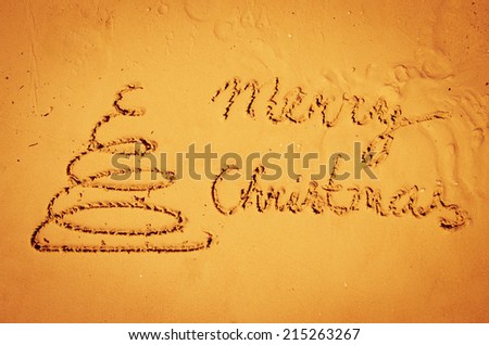 Christmas tree drawn into sand on beach