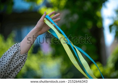 yellow and blue patriotic ribbon in a woman's hand fluttering in the wind, Ukrainian ribbon of freedom, colors of the flag of Ukraine as a symbol of courage, freedom and struggle for independence.