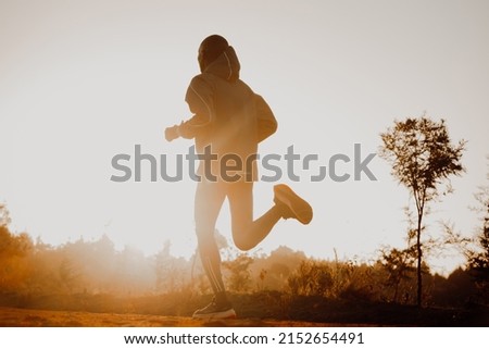 Silhouette of a kenyan runner running along a red dirt road near the city of Iten in Kenya. Athletic sports photo for long track and marathon runners
