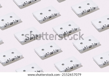 Pattern of white painted retro vintage cassette tapes on white background. Minimalist monochrome art concept.