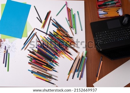 drawing workstation with colored pencils paper and laptop