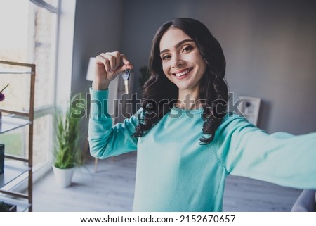 Photo of youth cheerful girl shooting selfie hold keys moving new apartament influencer blogger indoors