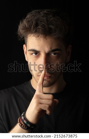close-up portrait black background young male handsome model with hand shut up don't talk listen expression visual expression Royalty-Free Stock Photo #2152673875