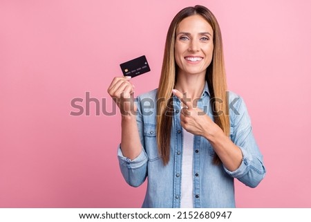 Photo of young cheerful woman indicate finger credit card benefit promo select isolated over pink color background