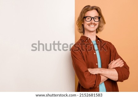 Portrait of attractive cheerful intellectual red-haired guy folded arms blank space isolated over beige pastel color background