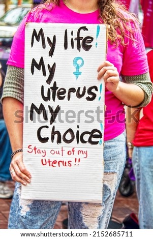 Unidentifiable young woman holding sign at pro choice rally reading my life my uterus my choice