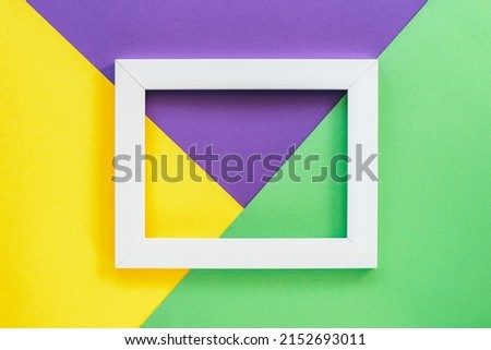 Three toned green, yellow and purple background with blank picture frame. Top view, flat lay.