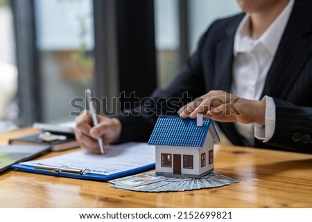 Real estate agent and customer make contract to buy and sell house and land. Approval of a contract to buy or sell a home. Offers mortgage loans and home insurance concept.