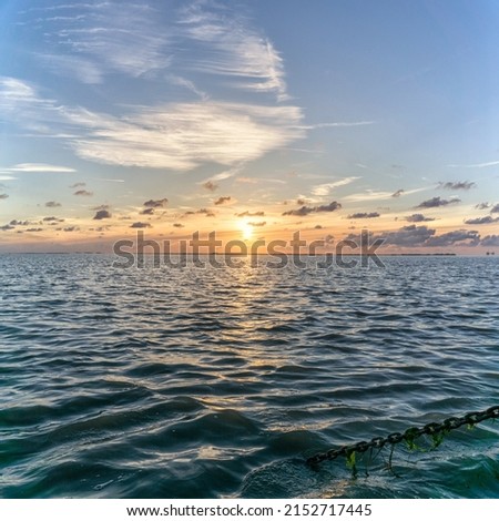 A vertical scenic shot of the sea during sunset under the sky and beautiful clouds