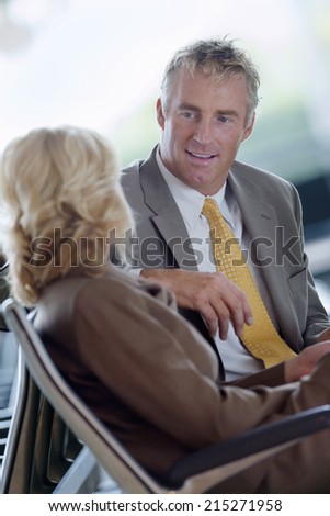 Businesswoman and businessman talking, smiling, side view (tilt)