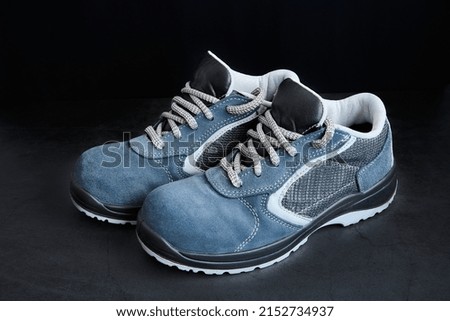 A closeup of blue male shoes with gray laces on a black background