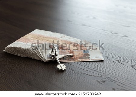 A pack of five thousand Russian rubles is spread out on the table. There are keys. Buying a house