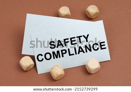The concept of industrial safety. On a brown surface, wooden cubes and a business card with the inscription - Safety Compliance
