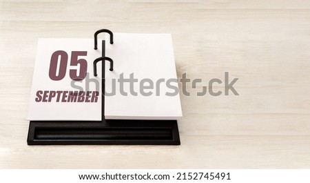 september 5. 5th day of month, calendar date. Stand for desktop calendar on beige wooden background. Concept of day of year, time planner, autumn month.