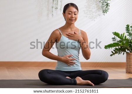Asian woman doing breathing exercise before practice yoga.Healthy female inhaling and exhaling to deep breath exercise for control and balance life with yoga meditation decrease stress, relax her mind Royalty-Free Stock Photo #2152761811