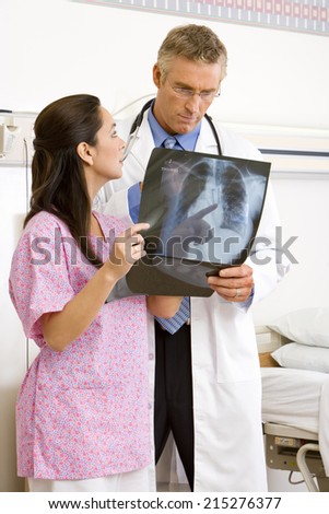 Young female nurse and mature male doctor looking at x-ray in hospital ward