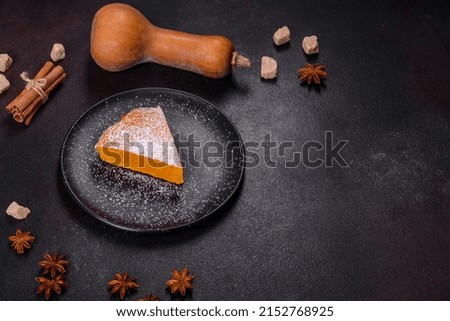 Pumpkin pie with whipped cream and cinnamon on a dark background, top view