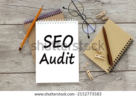 two notebooks with an inscription SEO AUDIT and glasses on a wooden table