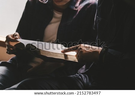 Concepts of Christianity. Two lovers reading the Holy bible by pointing to the character and to share the gospel to youth. The cross symbol, The books of the Bible. Royalty-Free Stock Photo #2152783497