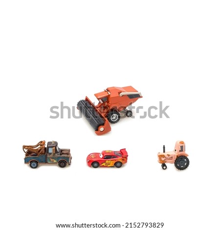 Children's toys from the cartoon combine-bull tractor-cow and two cars on a white background insulation