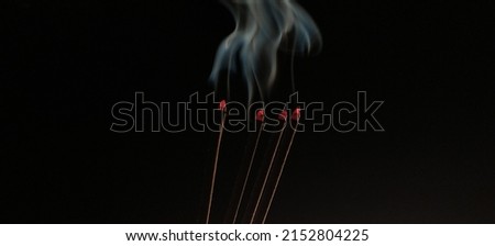 Aromatic agarbathi, agarbatti or Incense sticks smoldering in room with smoke and aroma. Isolated in dark black background with copy space. It used in asian religious prayer. Closeup macro side view. Royalty-Free Stock Photo #2152804225