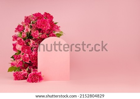 Fresh pink roses as arch, empty rounded door as podium on abstract pink scene mockup for presentation cosmetic products or goods, copy space. Bright romantic summer template for advertising, design.