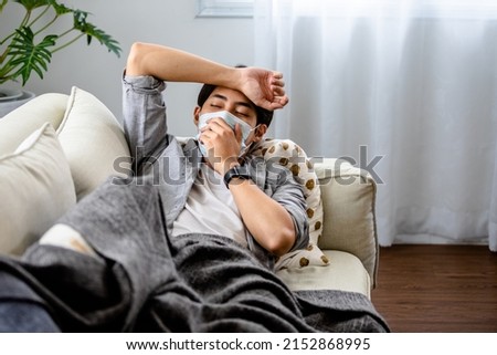Man Asian lying blanket on the sofa feeling sick headache with fever at home, Patients infected with Coronavirus or COVID-19, Home isolated, quarantined, observation of symptoms. Royalty-Free Stock Photo #2152868995