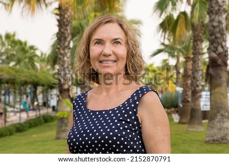 Portrait of a mature woman 50-60 years old against the backdrop of palm trees
