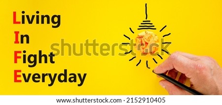 LIFE living in fight everyday symbol. Concept words LIFE living in fight everyday on yellow background. Businessman hand. Light bulb icon. Business LIFE living in fight everyday concept. Copy space.