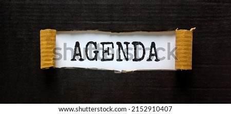 Business and agenda symbol. The concept word 'agenda' appearing behind torn black paper. Beautiful black background, copy space. Business and agenda concept. Royalty-Free Stock Photo #2152910407