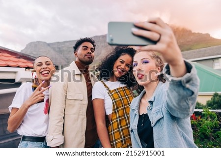 Group selfie on the rooftop. Four happy friends posing for a selfie while partying together outdoors. Group of multicultural friends having a good time together on the weekend.