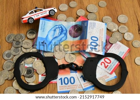 swiss money banknotes and coins with handcuff and police car 