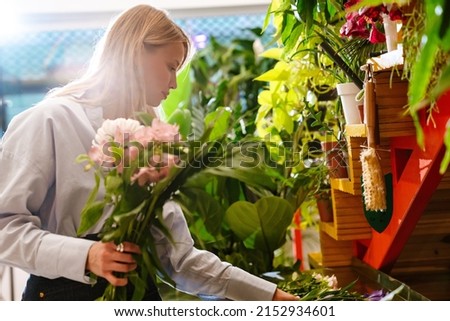 White beautiful young florist girl making bouquet with fresh flowers in shop