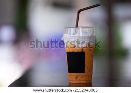 Light orange milk tea drink on wooden table in cafe.