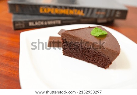 Chocolate cake decorated with chocolate sauce on a wooden table.