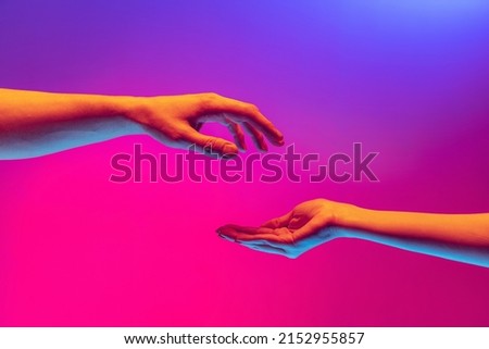 Love, care. Two authentic hands trying to touch each other isolated on gradient background in neon light. Concept of relationship, community, care, support, symbolism, culture Royalty-Free Stock Photo #2152955857