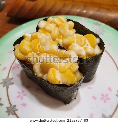 Two corn warships sushi on a flower-patterned plate.
The ingredients of sweet and savory corn warship sushi are corn, mayonnaise, rice, and seaweed. Royalty-Free Stock Photo #2152957483