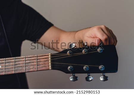 unrecognizable caucasian man indoors tuning acoustic guitar, front view and copy space. Royalty-Free Stock Photo #2152980153