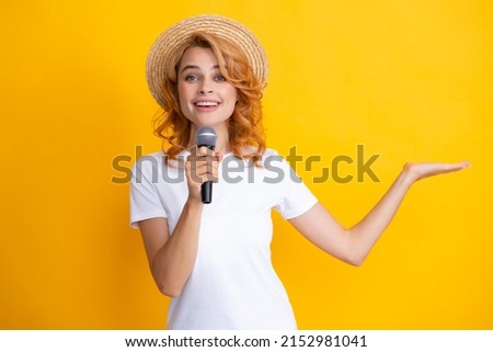 Stylish girl singing songs with microphone, holding mic at karaoke, posing against yellow background.